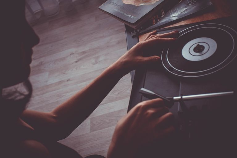 A person playing a vinyl record on a vintage turntable, creating a nostalgic mood.