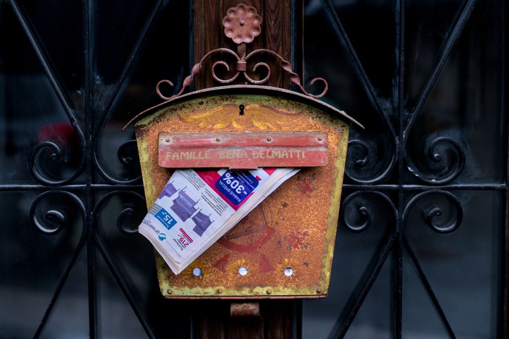Rustic rusted mailbox holding a newspaper in Saillon, Switzerland.